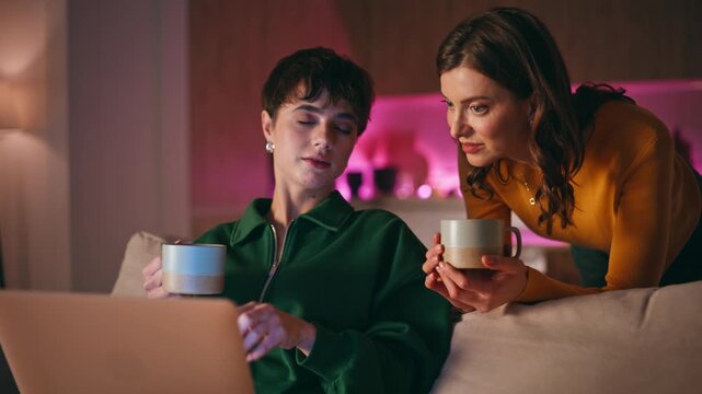 Friends discussing online shopping looking laptop in evening home closeup. 