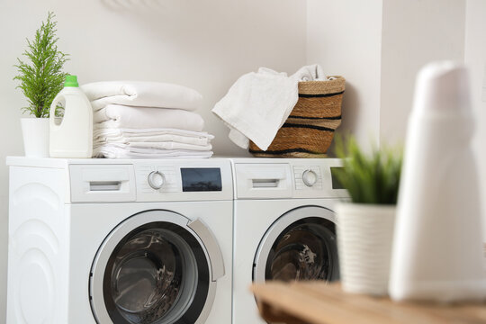 Stack of clean bed sheets on washing machine in bathroom