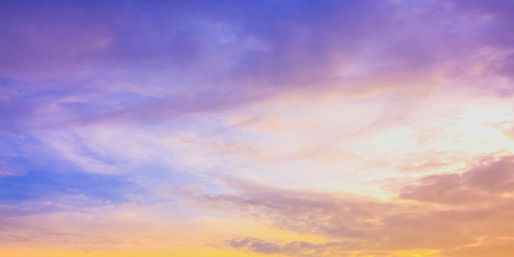 Beautiful vibrant twilight sky background with colorful pastel pink purple and golden orange clouds at sunset for inspirational nature wallpaper panorama