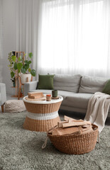 Obraz premium Interior of living room with sofa, coffee table and firewood in wicker basket