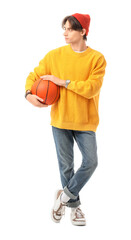 Fashionable young man in yellow sweater and hat with basketball ball on white background
