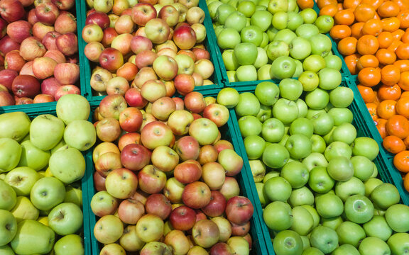 Fresh harvest of fruits on a market, green and red apples and tangerine.
