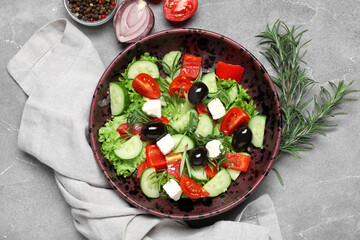 Bowl of tasty Greek salad, rosemary, vegetables and  peppercorns on grunge background