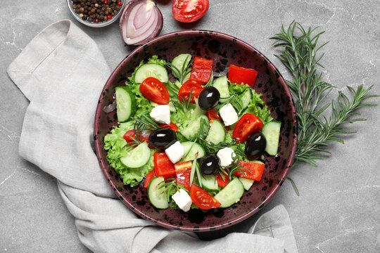 Bowl of tasty Greek salad, rosemary, vegetables and  peppercorns on grunge background
