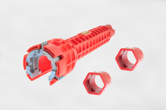 Red pipe wrench with hexagonal adapters. Clean, isolated presentation on white background. Tool designed for plumbing or pipe maintenance. High-contrast red color tool enhances visibility and appeal. 
