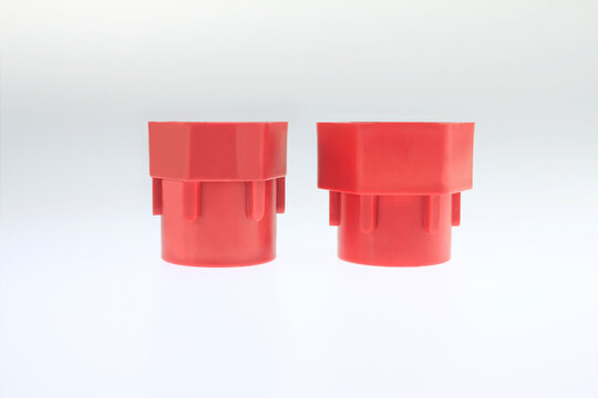 wo red plastic fittings stand side by side hexagonal socket adapters for multifunction basin wrench isolated on white background. Feature ridged sides cylindrical bases. Ideal for engineering projects
