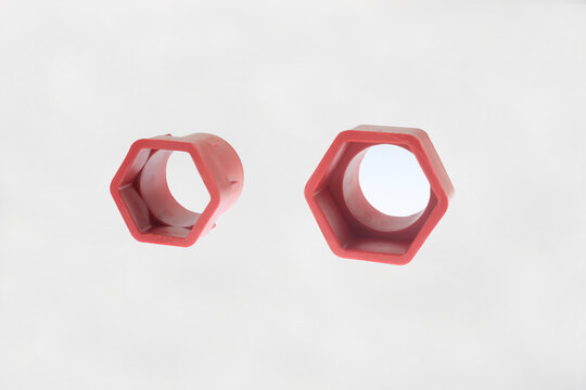 Two red plastic hexagonal socket adapters size 34mm and 40mm for multifunction faucet and sink installer wrench isolated on white background. Interchangeable jaw inserts for basin wrench 