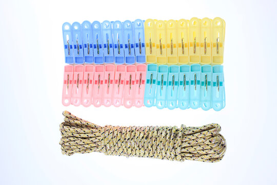Colorful clothespins neatly arranged with twisted rope below. Bright hues suggest playful, practical use. Colorful plastic clothespins and braided nylon utility rope arranged in clean composition 