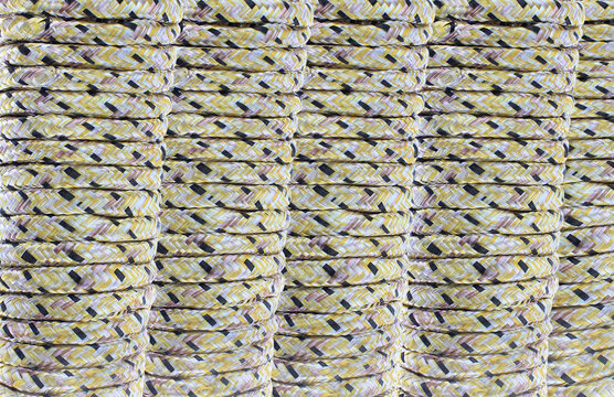 Stacked rope coils form a textured, repetitive pattern. Yellow and black threads create a bold contrast. Each coil tightens into neat, uniform shape.  Close up macro view of braided nylon utility rope