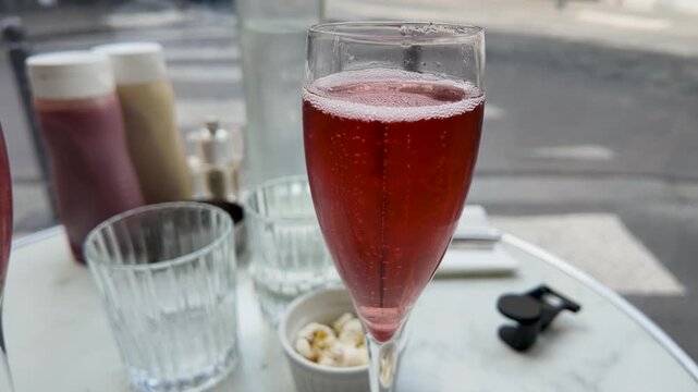 Red Champagne Cocktail on Marble Table at Outdoor Paris Sidewalk Cafe