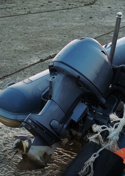 Dinghy engine, sea backdrop, low tide.