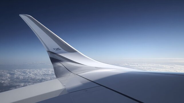 Sleek aeroplane wingtip soaring gracefully above fluffy clouds under a vast blue sky during daylight flight