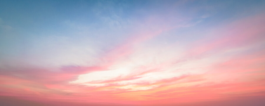 Beautiful vibrant twilight sky background with colorful pastel pink purple and golden orange clouds at sunset for inspirational nature wallpaper panorama