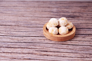 Fototapeta premium Kue Salju Soft, powdered treats rest in a wooden bowl. Warm wood grain adds rustic charm. Minimalist background emphasizes sweet delicacy. Gentle lighting enhances inviting texture. Ideal for food 