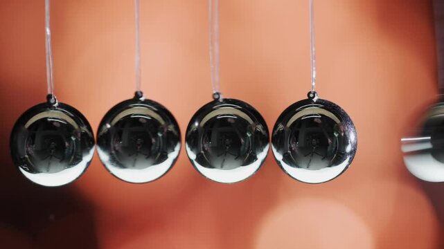 Newton's cradle demonstrates laws of motion and energy transfer with swinging metal balls.