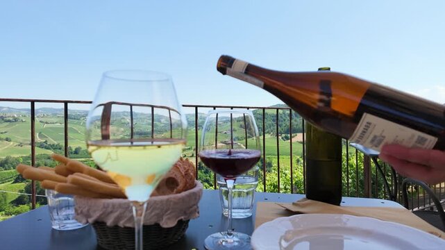 Pouring Red Wine on a Scenic Terrace Overlooking Italian Vineyards