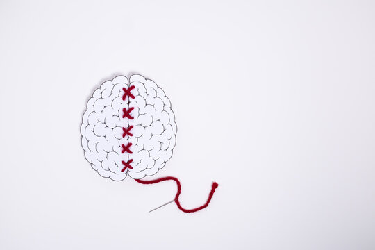 Conceptual brain illustration repaired with red stitching thread. Symbolizes psychological healing, recovery, therapy, resilience and rebuilding mental strength after emotional challenges.