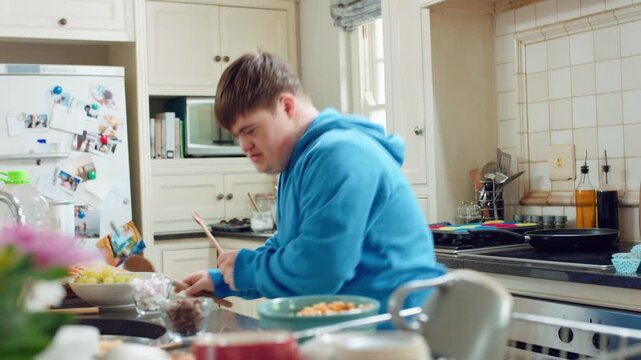 Music, cooking and man with spoon in kitchen for lunch, meal prep and ingredients for cuisine. Home, happy and person with down syndrome with rhythm, audio and track by counter for dinner recipe