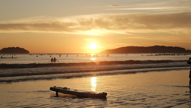 Beautiful golden sunset at Tanjung Aru Beach with a paddleboard on the shore, Kota Kinabalu.