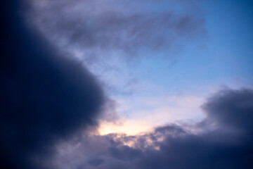 Fototapeta premium Soft white and orange cloud catching the last rays of sunlight in a clear blue evening sky. Simple and tranquil nature background. 