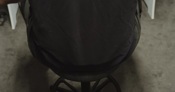 Rear view of a man sitting on an ergonomic office chair at a workstation. Concept of workplace ergonomics, office comfort, healthy sitting posture, productivity, and modern office furniture.
