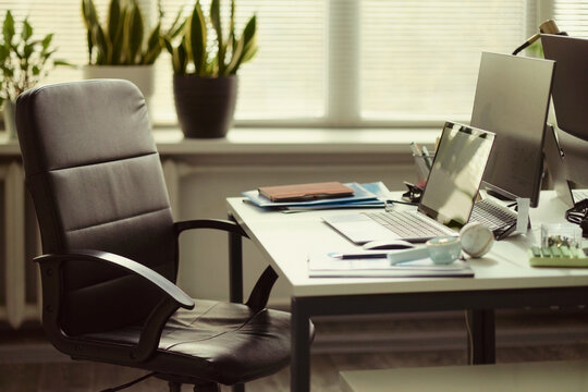 Office workstation standing ready with laptop, monitor, documents, signaling organized business workflow and employee absence. Wide shot, useful for remote work, productivity, staffing themes