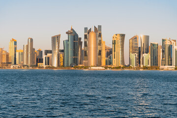 Obraz premium Cityscape panorama of modern skyscrapers and waterfront against a clear sky.