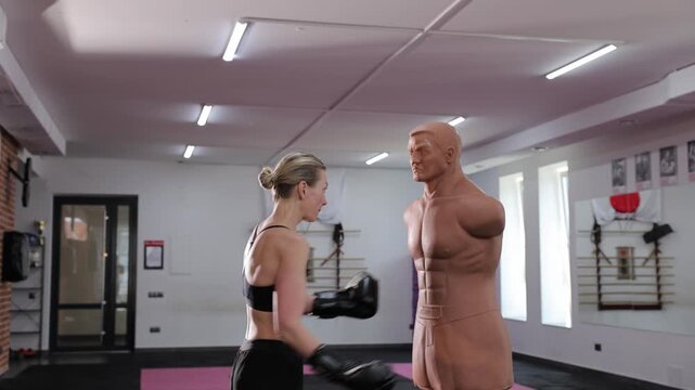 Determined woman punching training dummy during workout