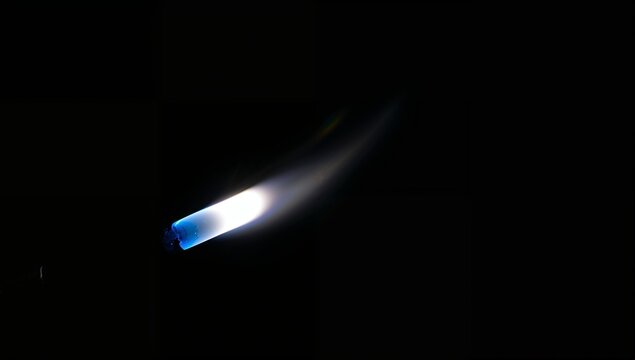 Close-up of a matchstick igniting with bright flame against black background