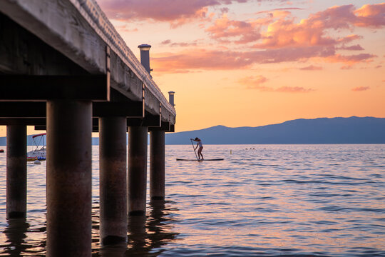 Paddle Boarder on Lake Tahoe at Sunset with Dock in the side foreground