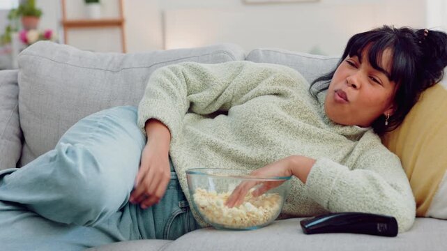 Popcorn eating, watching tv and woman on living room sofa with comedy movie, relax with comic film and happy with subscription service on the couch. Girl with food and funny television show in house