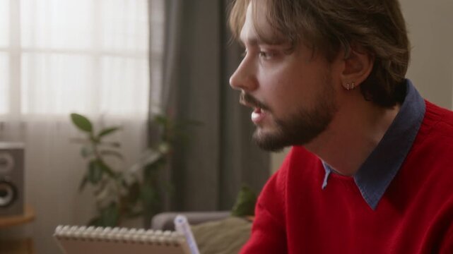 Close up tilt up shot of game master enthusiactically explaining game rules while holding notebook and pen in cozy living room