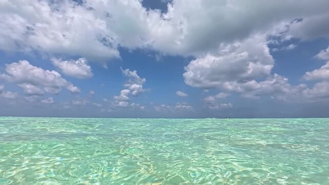 水面ギリギリの視点で進む百合が浜へ向かう夏のヨロンブルーの海と青空（与論島）