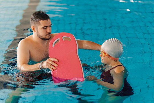 Swimming instructor teaching little girl a swimming pool lesson