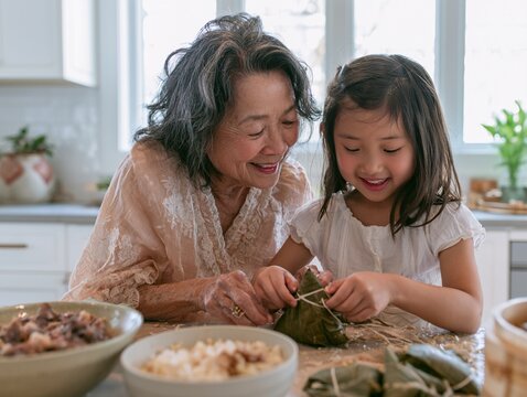 Asian Grandmother Teaching Granddaughter to Make Traditional Zongzi Dumplings for Dragon Boat Festival.