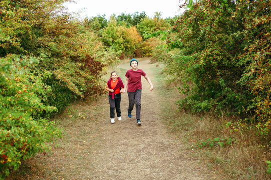 Happy siblings running through countryside trail