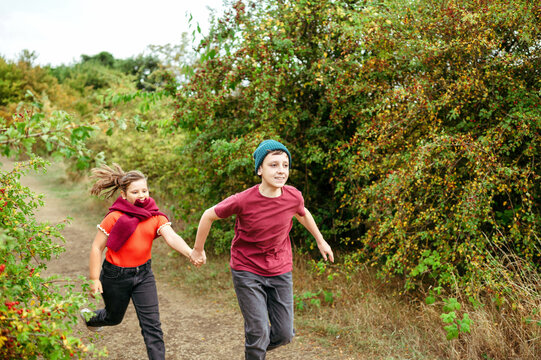 Playful brother and sister running together through the park