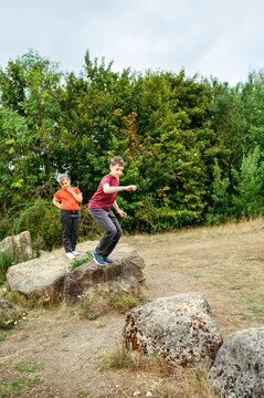 Teenager boy jumping between rocks during countryside adventure