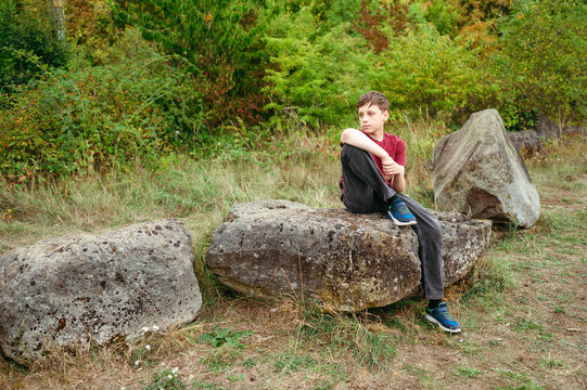 Teenager boy relaxing on rock during peaceful countryside adventure