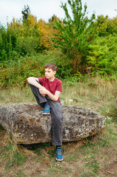 Teenager boy sitting on rock during countryside outdoor adventure