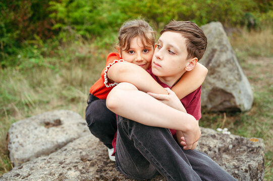Child girl hugging teenager brother during peaceful countryside moment