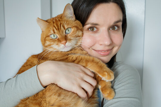 Cute selfie portrait of domestic orange cat and brunette girl at home