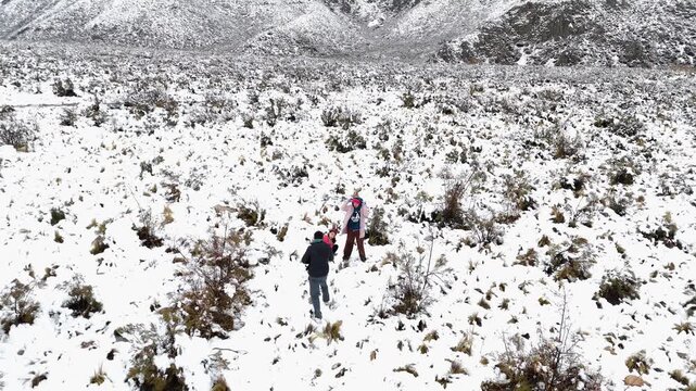 people playing in the snow next to snowy mountains