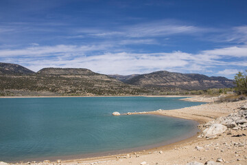 Obraz premium Curved Sandy Shoreline Along Mountain Lake