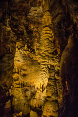 Naklejka premium Stalactites and stalagmites seen in a cave with light illuminating