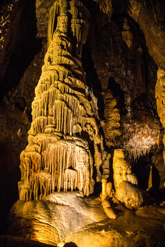 Stalactites and stalagmites in a cave with warm lighting on rock