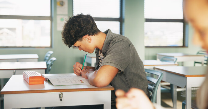 Student, boy and writing in classroom with assessment, english test or high school education for growth. Teenager, notes or learning in academy with knowledge development, language exam or assignment