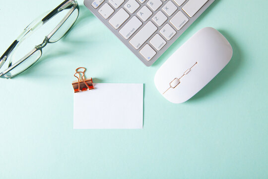 Office desk table with keyboard, mouse, pen, paper clips and glasses. Top view with copy space