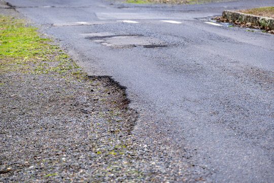 A deteriorated asphalt road surface showing extensive cracking, crumbling edges, and pothole damage. Concept of the need for road repair and infrastructure maintenance issue in Australia