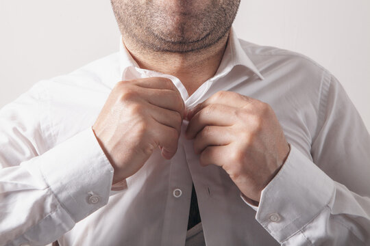 Man unbuttons his white shirt. Close-up of a man in white shirt